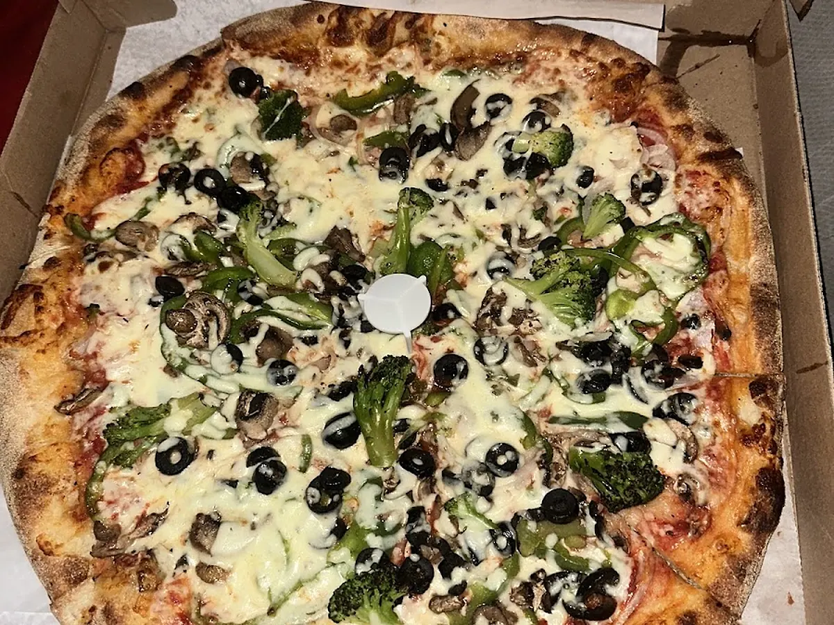 Greek pizza with olives, feta and spinach in the box
