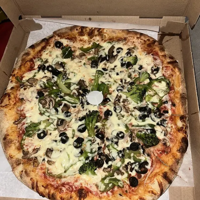 Greek pizza with olives, feta and spinach in the box